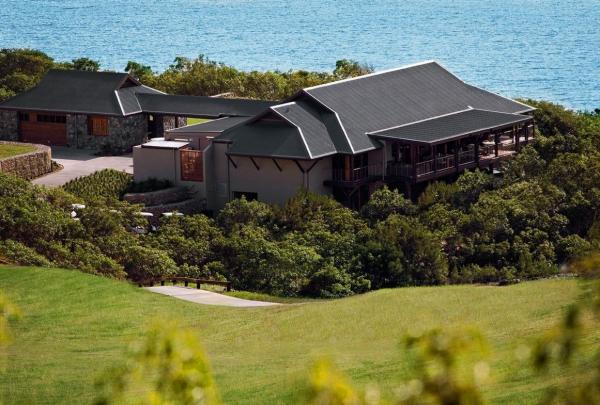The modern clubhouse of Hamilton Island Golf Club, Queensland, is nestled in lush greenery overlooking the bright blue Whitsundays ocean. The timber building features large decks designed to take in the tropical island views. © Tourism Australia