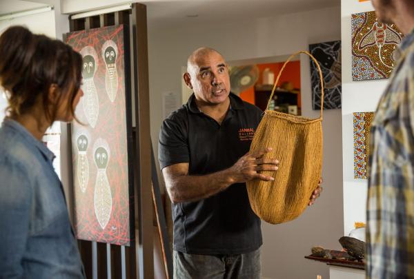 Guide showcasing Aboriginal art at Janbal Gallery, Down Under Tours - Daintree Dreaming, Mossman Gorge, Queensland © Tourism Australia