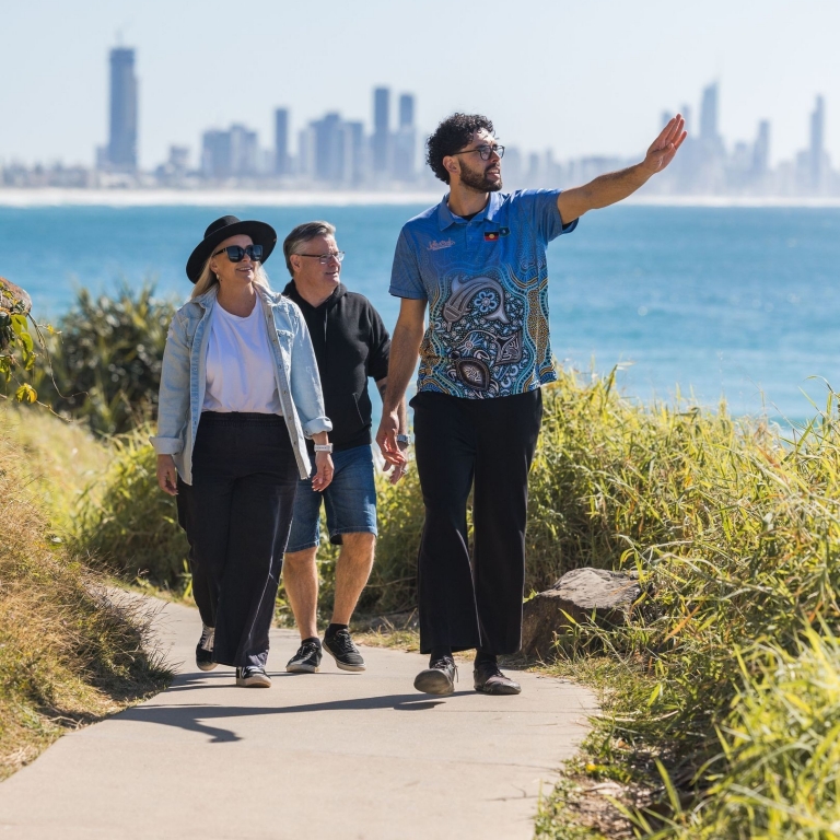 A friendly guide from the Jellurgal Aboriginal Cultural Centre engages warmly with a group of tour participants, Walkabout Tour, Burleigh Heads, Queensland © Tourism Australia