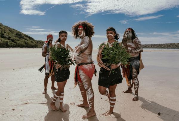 On the sandy shores of Tallebudgera Creek, Yugambeh Aboriginal Dancers stand proudly, Walkabout Tour, Jellurgal Aboriginal Cultural Centre, Burleigh Heads, Queensland © Tourism Australia