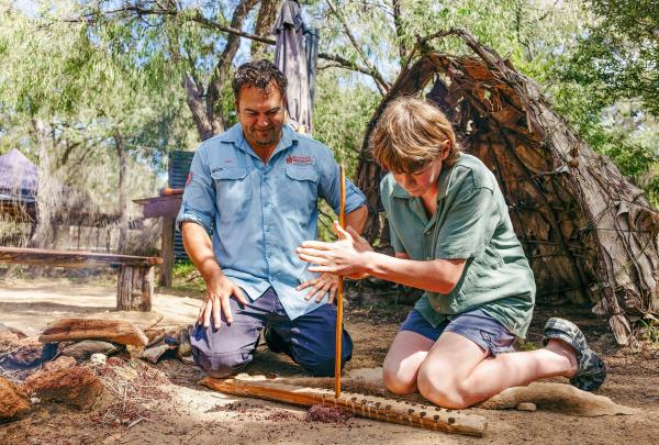 Guide helping woman learn fire-making, Koomal Dreaming, Yallingup, Western Australia © Tourism Australia