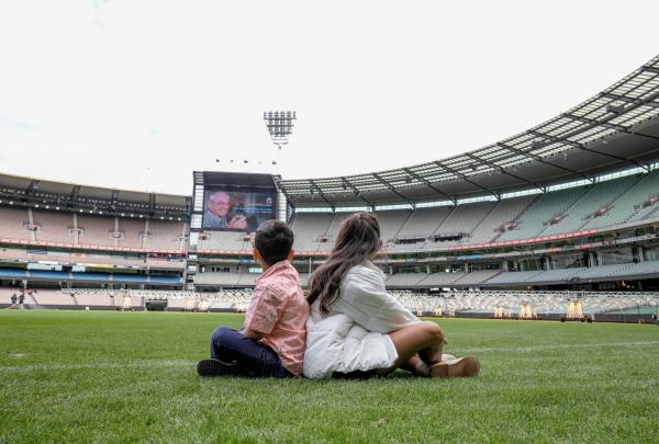 Two children sitting on the grounds of the MCG oval, Melbourne Cricket Ground, East Melbourne, Melbourne, Victoria © Tourism Australia