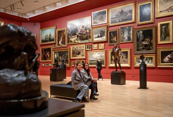 Two women sitting looking at artworks in the Red Room of the National Gallery of Victoria, Melbourne, Victoria © Tourism Australia