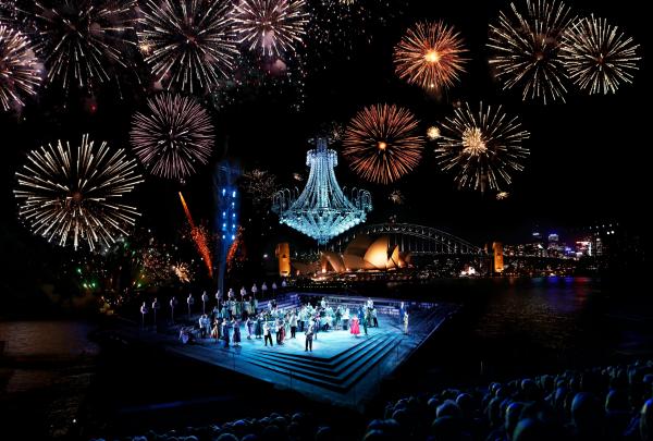 A stage on the banks of the Sydney Harbour with fireworks exploding in the sky at Handa Opera on Sydney Harbour, Sydney, New South Wales © Tourism Australia