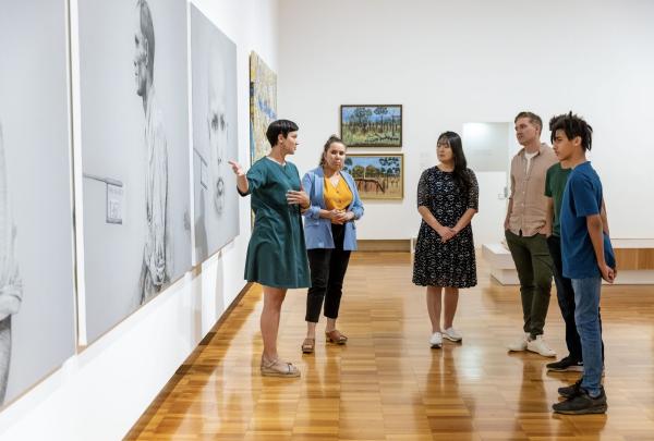 Gallery guides talking to group of talent next to artwork, Brisbane, Queensland © Tourism Australia