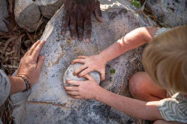 Close up overhead of a boy using traditional grinding stones as part of an Indigenous tour experience in the Dampier Peninsula, Western Australia  © James Fisher Photography/Tourism Australia