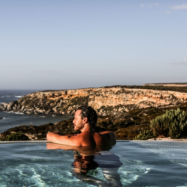 Man in the pool at Southern Ocean Lodge, looking out over the coastline of Kangaroo Island, South Australia © Tourism Australia