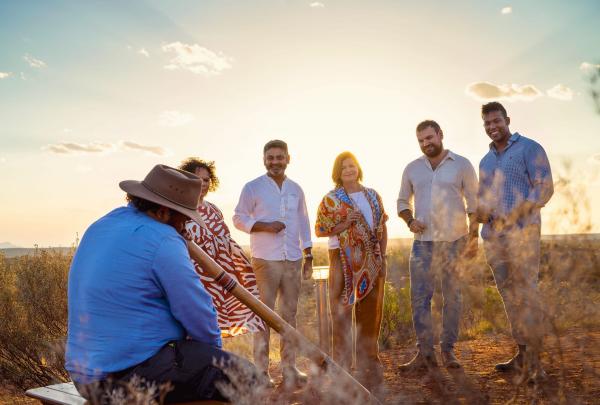 Guide playing the didgeridoo for a group of people, Voyages Indigenous Tourism Australia, Uluru-Kata Tjuta National Park, Northern Territory © Tourism Australia