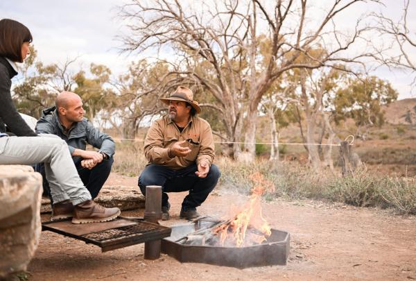 Guests and guide sitting around a fire, Flinders Ranges, South Australia © Tourism Australia