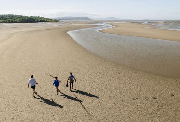 In this aerial image, two individuals and their guide are strolling along Cooya Beach in Mossman, Tropical North Queensland, Queensland © Tourism Australia